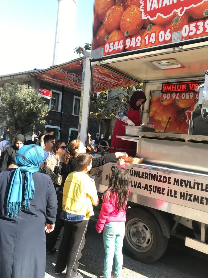 Mobil lokma aracı önünde sıraya giren misafirlere lokma ikramı